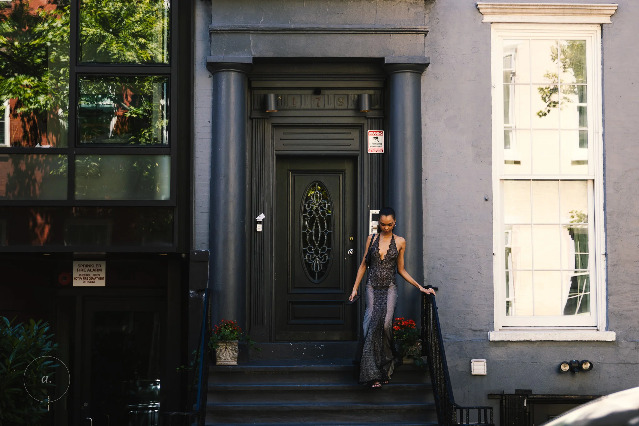 A woman in a long dress stepping down from the door of a grey townhouse, New York, photographed by Campbell Jensen