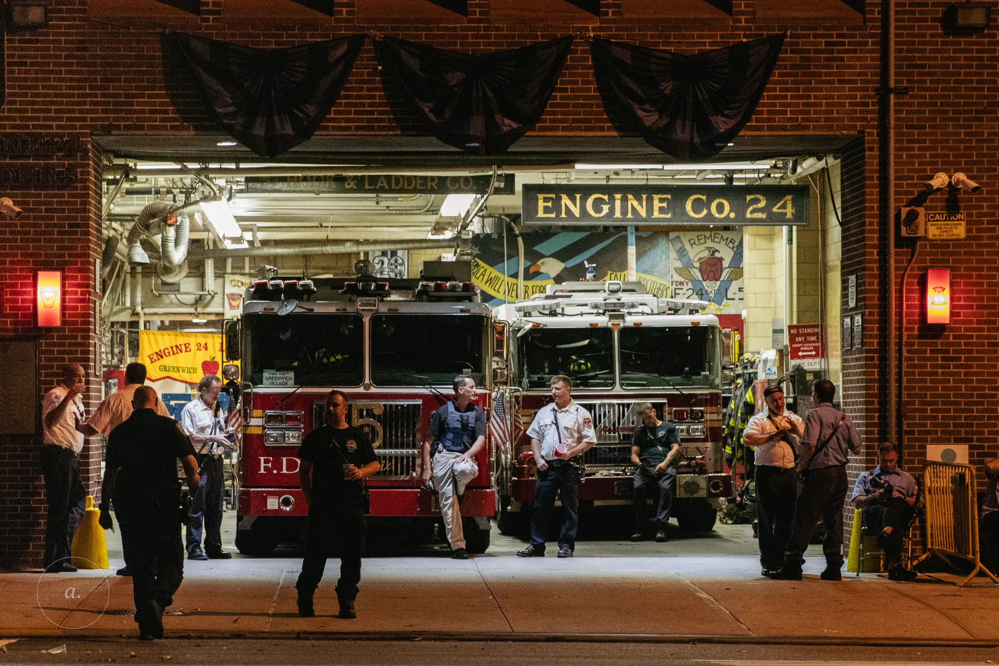 Firefighters gathered in the open bay of a firehouse at night, New York, photographed by Campbell Jensen